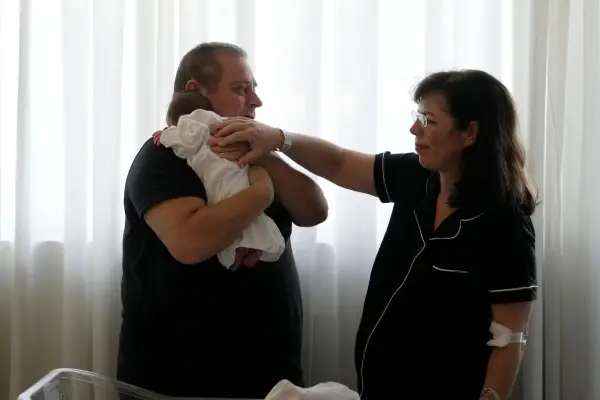 Костянтинос Раптіс, 60 років, справа, і його дружина Христина Рапті-Целепі, 54 роки, ніжно торкаються своєї триденної доньки Ґіорґії у приватній пологовій клініці в Афінах, Греція, у п'ятницю, 11 вересня 2026 року. (AP Photo/Thanassis Stavrakis)